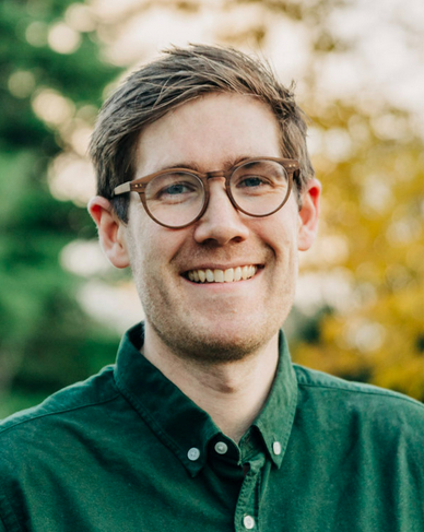 Thor Haakon Bakke in a green shirt on an unfocused background of green and yellow trees and a grey sky